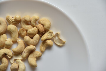 Cashew nuts on a white plate in a group of loose