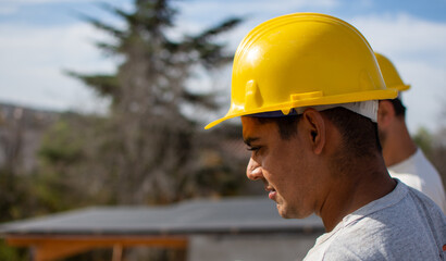 male builder performs work on the roof, fastens corrugated sheets