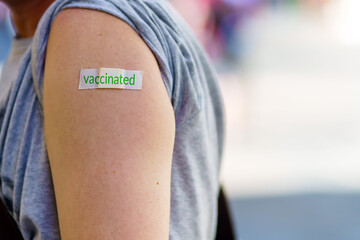 A person's shoulder after vaccination. The patch with the inscription is vaccinated.