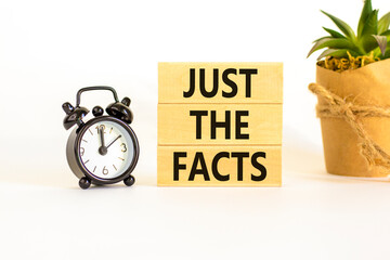 Just the facts symbol. Concept words Just the facts on wooden blocks on a beautiful white table white background. Black alarm clock. Business and just the facts concept. Copy space.