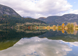 Autumn landscape by the lake Bohinj in Julian Alps. Fascinating reflectins in the lake on a cloudy day.