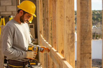 bricklayers with yellow helmet and protective glasses screwing on wood - PHOTO SESSION: WORK IN...