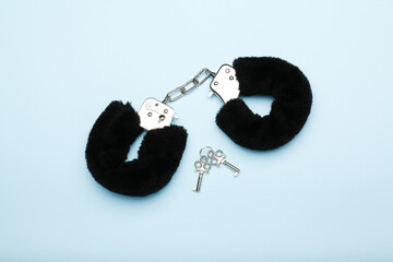 black fluffy handcuffs for adults on a blue background. sex toy