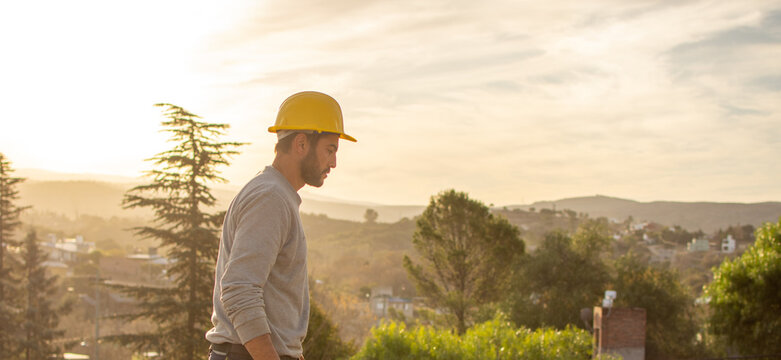 bricklayers with yellow helmet and protective glasses building on a roof with a sunset - PHOTO SESSION: WORK IN CONSTRUCTION