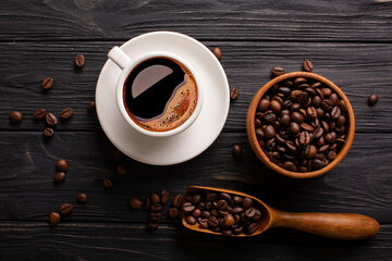 Obraz na płótnie Canvas Wooden table with coffee beans in scoop composition. Vintage wood background texture and old spoons with grains top view