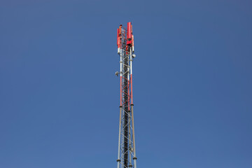 Antennenmast für Mobiltelefone als Gitterrohrmast rot und weiß gestrichen vor einem blauen...
