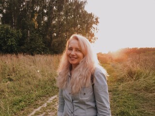 Portrait of a happy and beautiful blonde middle aged woman in the field. Joyful lady looking into the camera outdoors.