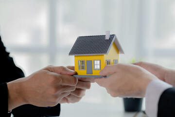 Real estate agents are carrying a housing model of the project to be forwarded to customers as home delivery. Real estate trading ideas and bank loans for buying and selling houses and land.