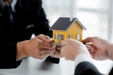 Real estate agents are carrying a housing model of the project to be forwarded to customers as home delivery. Real estate trading ideas and bank loans for buying and selling houses and land.
