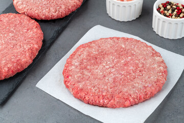 Raw meat hamburger over wooden board with seasonings