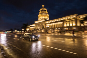Old car on streets of Havana with colourful buildings in background. Cuba