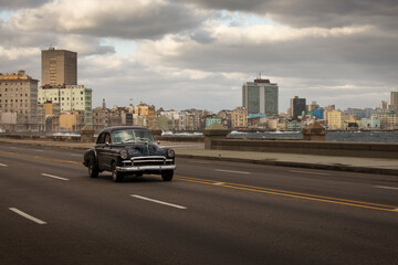 Old car on Malecon street of Havana with storm clouds in background. Cuba