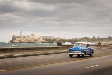 Fototapeta na wymiar Old car on Malecon street of Havana with storm clouds in background. Cuba