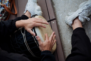 Fototapeta premium The guy's hands virtuosically bang fingers on the drum, the African drum djembe man plays music on the street, the instrument of percussion, the percussion surface.