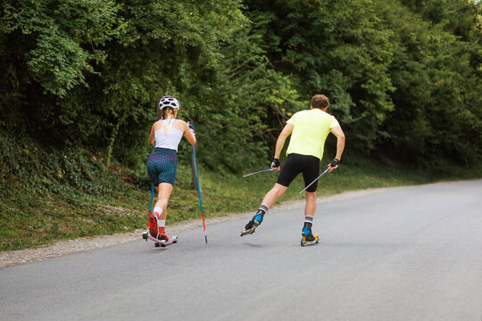 Athletic woman and man together training on the roller ski. Back view. Copy space. Concept of competition, biathlon, and summer workout