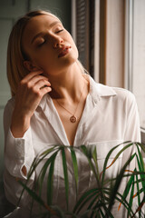 Delicate and sensual blonde in a white silk blouse and with a decoration around her neck - 514057037
