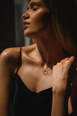Attractive blonde woman in a black silk tank top and neck jewelry - 514057074