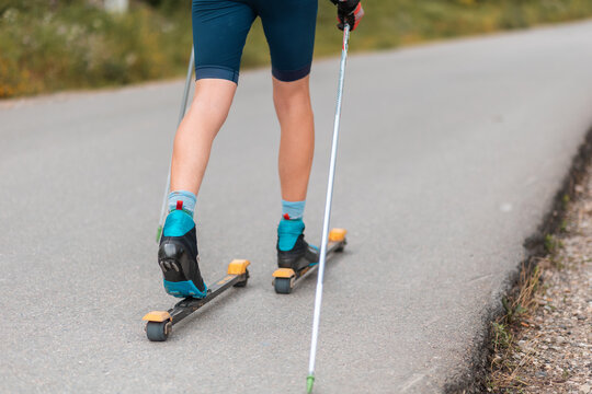 Legs of a biathlete athlete with ski poles, close-up. Concept of rollers ski and summer workout