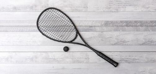 Black squash racket and ball on grey court. Horizontal sport theme poster, greeting cards, headers,...