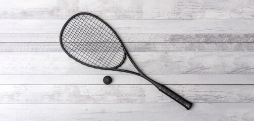 Black squash racket and ball on grey court. Horizontal sport theme poster, greeting cards, headers, website and app