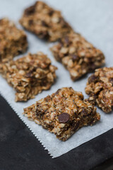 peanut butter chocolate chip granola bars with oats on white parchment paper with neutral background