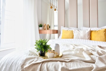 Modern bedroom with window and bed with white sheets and yellow pillows. Interior of room with minimalism and stylish design.