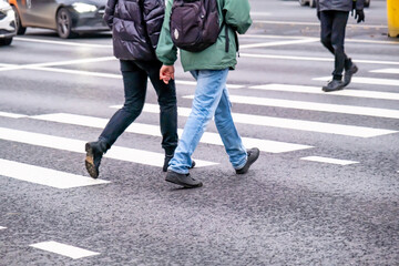 A couple of people cross a pedestrian crossing holding hands.