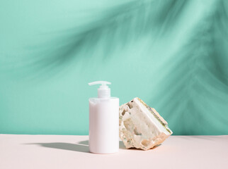 Fototapeta na wymiar Cosmetic bottle of white color on a podium made of natural stone, blue background with deep shadows