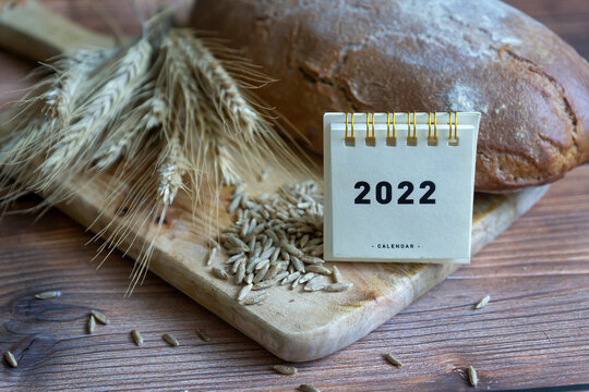 Black bread, spikelets and zeno with cornflowers and a 2022 calendar on a wooden table background.