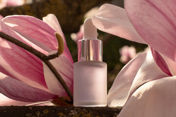 Cosmetic bottle dropper among the magnolia flowers
