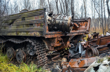 Fototapeta na wymiar Broken abandoned rusty old combat vehicle and other military equipment