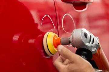 Worker polish a red car. Car detailing - Men using machinery car polishers maintenance to remove...