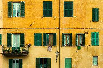 Fototapeta na wymiar Facades of old buildings in Florence, Italy. Old house near Firenze canal with yellow walls and green blinds.