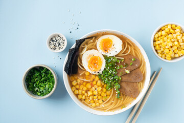 Fototapeta na wymiar Ramen noodle soup bowl with egg on blue background. Top view