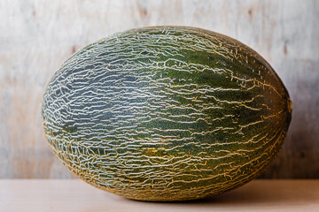 Whole piece of melon, on wooden background.