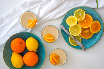 Top view of chia pudding with lemon and orange with a cloth. Orange and lemon slices in a blue color bowl. Summer, vivid colors.
