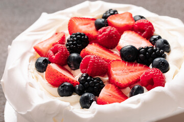 Pavlova meringue cake with fresh berries on brown background