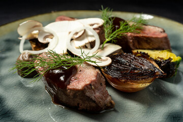 Grilled beef with barbecue sauce on a plate with mushrooms, herbs, rosemary, grilled onion and avocado