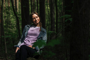 portrait of a beautiful girl in the forest in the rays of the sun breaking through the trees