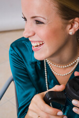 Woman with necklace holding cup, smiling