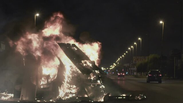 Dramatic Scene of a Car on Fire at Night on an Empty Road - Zoom In