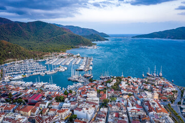 Naklejka premium Aerial view of Marmaris harbor with yacht and sailboat. Colorful landscape of evening Turkish city.