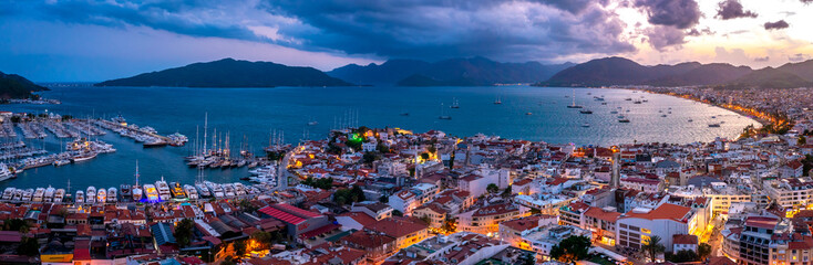 Fototapeta na wymiar Aerial view of Marmaris harbor with yacht and sailboat with evening lighting. Colorful landscape of the night Turkish city. Beautiful sky at sunset