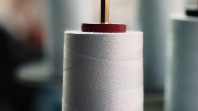 The thread is unwound from the spool while sewing by a seamstress on a sewing machine