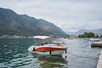 Fototapeta na wymiar Small yacht with tent roof is moored in Kotor bay