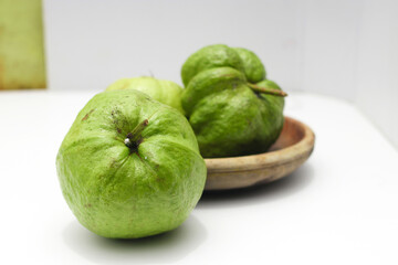 a group of fresh ripe Crystal guava (Psidium guajava) on a wooden plate isolated on white background