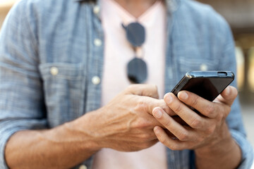 Closeup of business man hands using mobile app shopping online, checking email, sending text message outdoors, selective focus. Technology concept