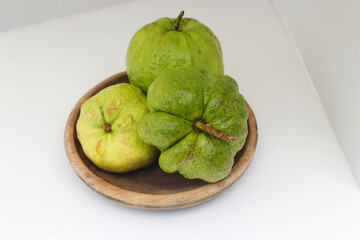 a group of fresh ripe Crystal guava (Psidium guajava) on a wooden plate isolated on white background
