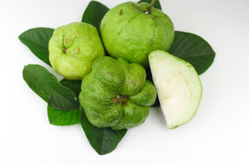 a group of fresh ripe Crystal guava (Psidium guajava) on green leaves isolated on white background.