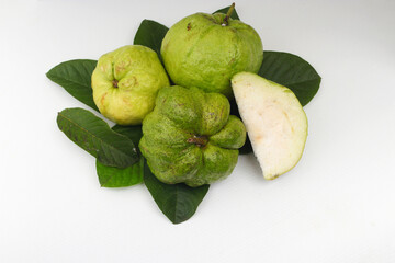 a group of fresh ripe Crystal guava (Psidium guajava) on green leaves isolated on white background.